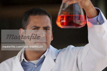 Mature scientist looking at liquid in volumetric flask