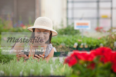 Young woman looking at plants in garden centre, smiling