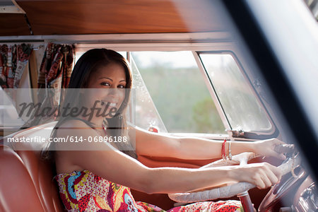 Young woman driving camper van and smiling, portrait
