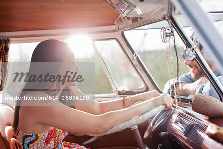 Young woman in camper van and smiling at boyfriend