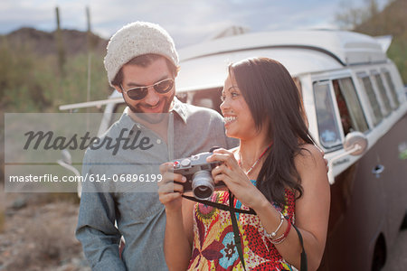 Young woman holding camera with boyfriend on road trip, smiling