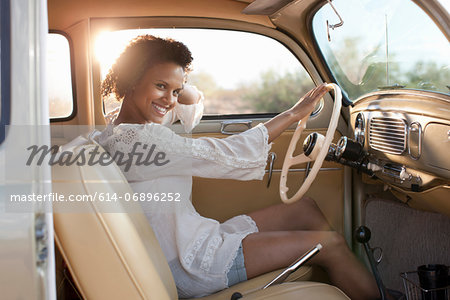 Young woman sitting in car on road trip, portrait