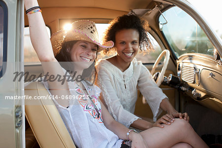 Young women sitting in car on road trip, portrait