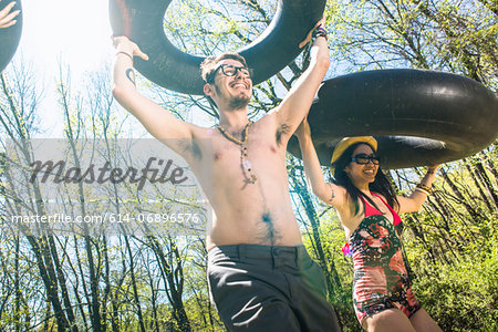 Couple carrying inner tubes above head