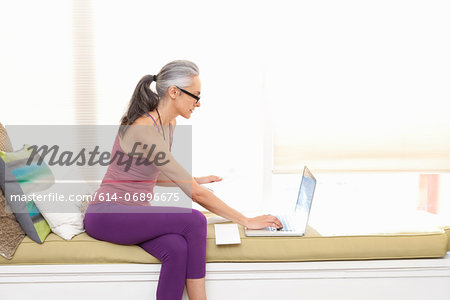 Woman sitting on window seat using laptop