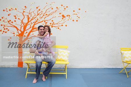 Father with two daughters in front of tree mural on wall Father with two daughters in front of tree mural on wall