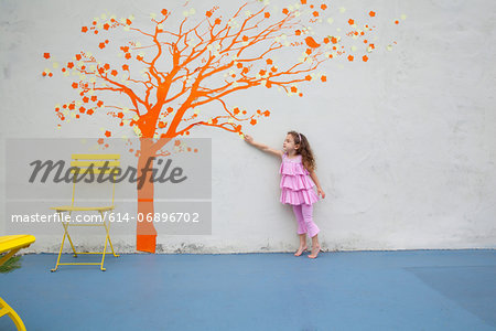Girl pointing to orange tree mural on wall Girl pointing to orange tree mural on wall