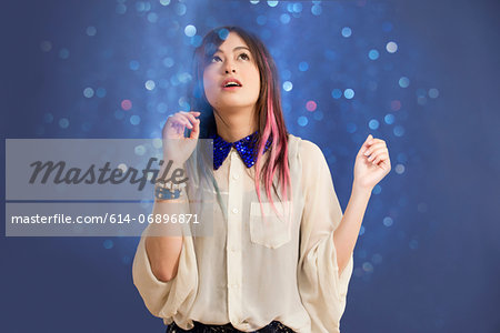 Portrait of young woman looking up at glitter