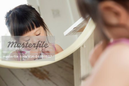 Mirror portrait of toddler fastening dress buttons