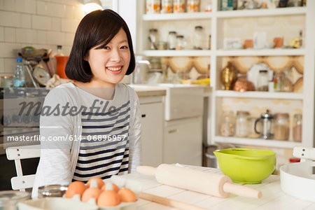 Portrait of young woman at kitchen table with baking ingredients