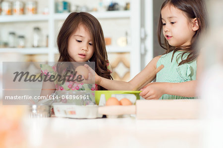 Two young sisters learning how to bake