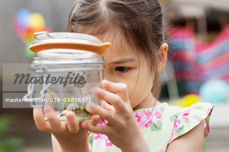 Young girl studying jar of snails