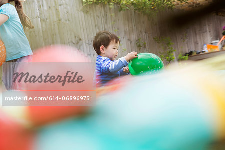 Male toddler playing in garden with balloon