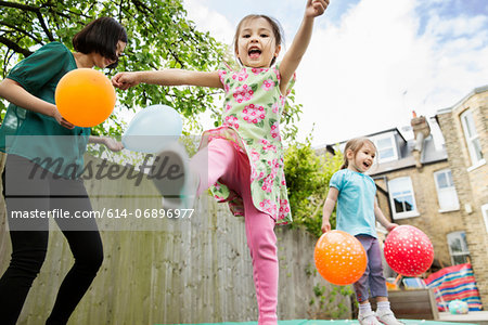 Mother and daughters playing in garden with balloons