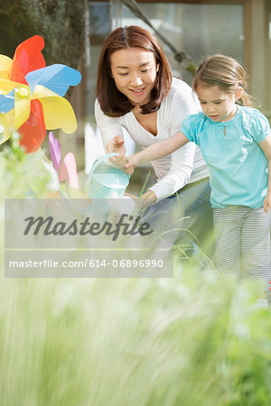 Mother and young daughter with watering can and toy windmill