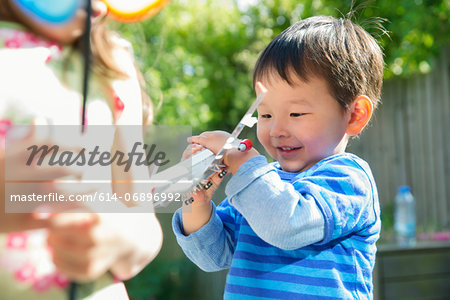 Male toddler in garden with toy airplane