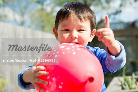 Male toddler in garden with red balloon