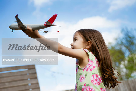 Young girl in garden playing with toy airplane