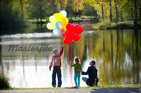 Mother and children in front of lake with bunches of balloons