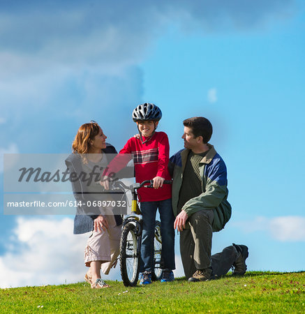 Mother and father encouraging son to ride bicycle