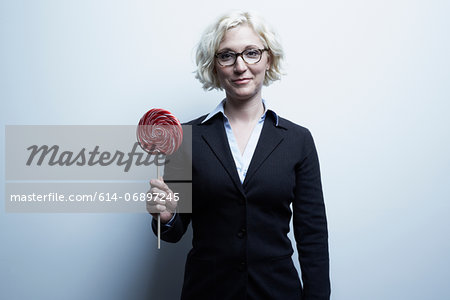 Studio portrait of blond businesswoman with red lollipop