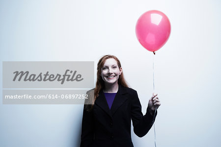 Studio portrait of young businesswoman holding red balloon