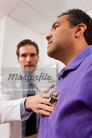 Mid adult doctor using stethoscope on patient