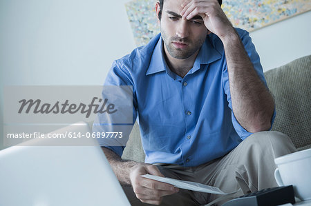Worried man with hand on head holding bills