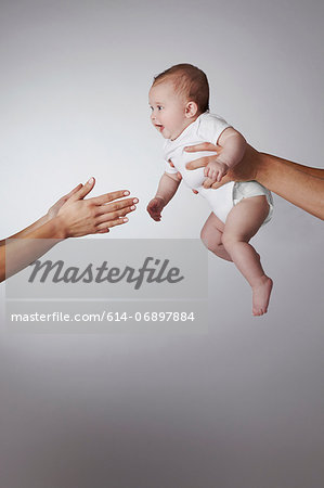 Parents passing baby daughter to each other