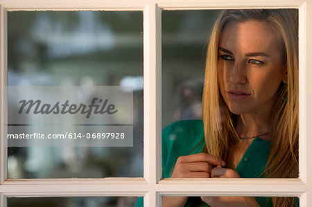 Portrait of young woman looking through window Portrait of young woman looking through window
