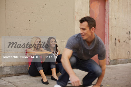 Man skating past women sitting on ground