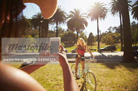 Woman photographing friend on bicycle