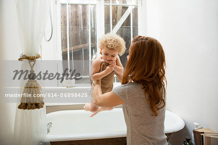Mother lifting child from bathtub