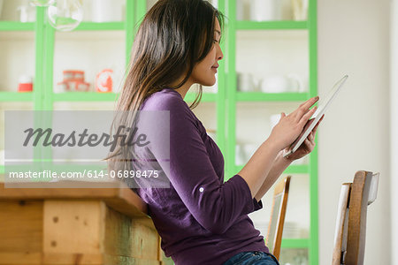 Woman leaning against table using digital tablet