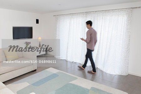 Man with mobile phone walking past curtains