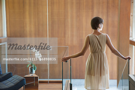 Woman standing at top of stairs in modern house Woman standing at top of stairs in modern house