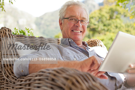 Portrait of smiling man using digital tablet on patio