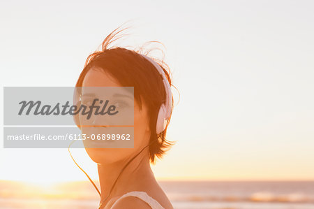 Close up portrait of confident woman wearing headphones at beach