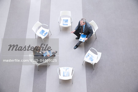 High angle view of businessman and businesswoman talking at chairs in circle
