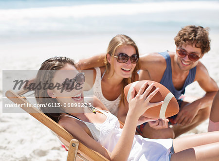 Smiling friends with football on beach Smiling friends with football on beach