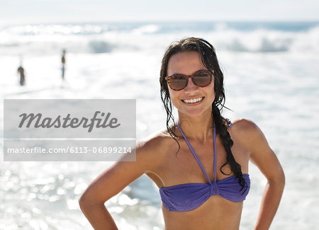 Portrait of smiling woman in bikini and sunglasses at beach