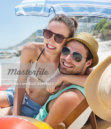 Portrait of smiling couple wearing sunglasses on beach
