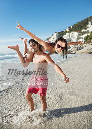 Portrait of happy man lifting woman on beach