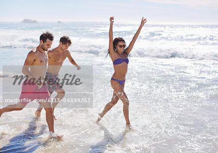 Enthusiastic friends running and splashing in ocean