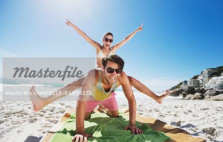 Enthusiastic couple piggybacking on beach