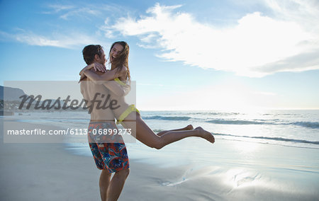 Happy couple hugging and spinning on beach