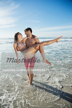 Man carrying woman in ocean surf