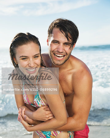 Close up portrait of happy couple hugging on beach