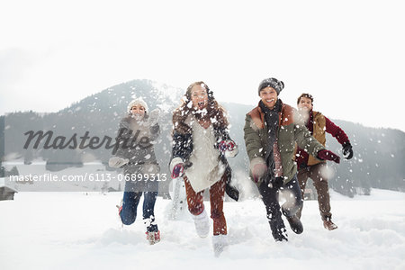 Happy friends playing in snowy field