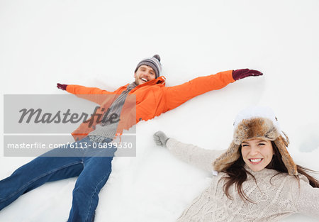 Portrait of happy couple making snow angels